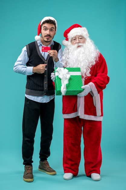 Photo gratuite vue de face du père noël tenant un cadeau avec un jeune homme