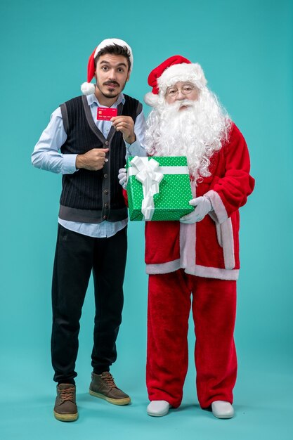 Vue de face du père noël tenant un cadeau avec un jeune homme