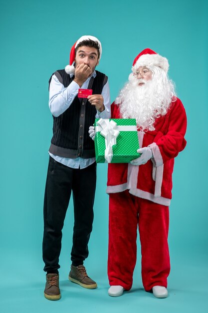 Vue de face du père noël tenant un cadeau avec un jeune homme