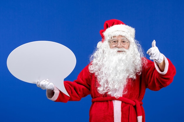 Vue de face du père noël tenant une grande pancarte blanche sur un bureau bleu couleur neige noël vacances