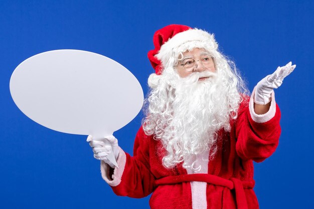 Vue de face du père noël tenant une grande pancarte blanche sur la couleur bleue des vacances de neige noël