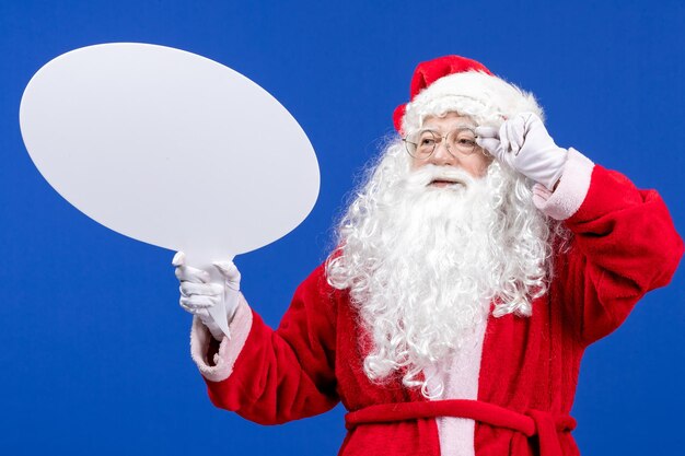 Vue de face du père noël tenant une grande pancarte blanche sur la couleur bleue des vacances de neige noël