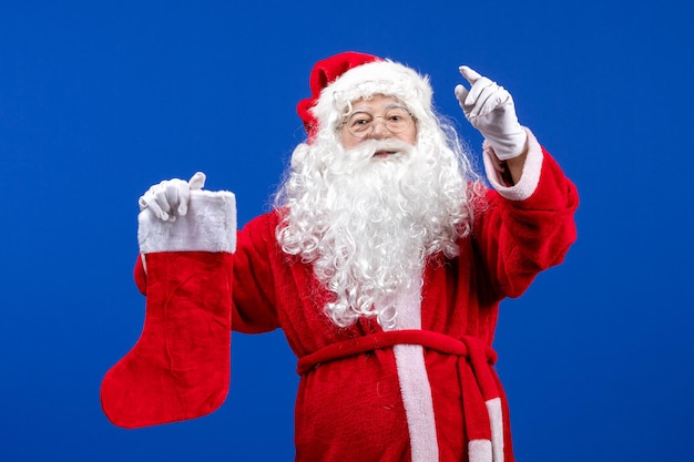 Vue de face du père noël tenant une grosse chaussette de noël sur la neige de noël de couleur de sol bleu