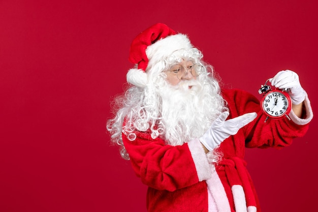 Vue de face du père noël tenant une horloge sur le temps d'émotion du nouvel an des vacances de noël rouge