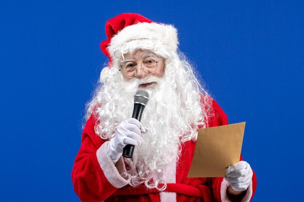 Vue De Face Du Père Noël Tenant Un Micro Et Lisant Une Lettre Sur Le Nouvel An Bleu Neige Couleur Vacances Noël