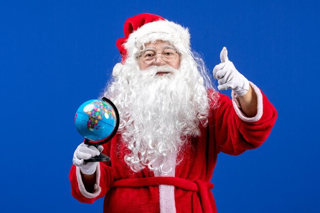 Vue de face du père noël tenant un petit globe terrestre sur les vacances de noël couleur bleu nouvel an