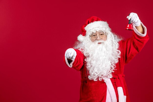 Vue de face du père noël tenant une petite cloche sur le cadeau rouge émotion noël nouvel an vacances