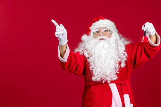 Vue de face du père noël tenant une petite cloche sur un cadeau rouge émotion noël vacances du nouvel an