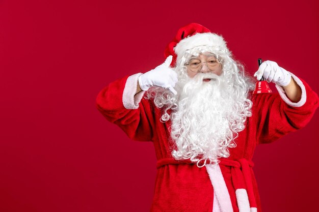 Vue de face du père noël tenant une petite cloche sur les cadeaux du nouvel an de noël rouge vacances d'émotion