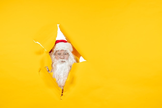 Photo gratuite vue de face du père noël à travers le mur jaune déchiré