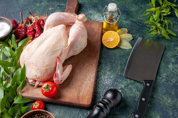 Vue de face du poulet frais avec des tomates rouges sur un repas de cuisine bleu foncé photo d'animal couleur de viande de poulet nourriture de ferme