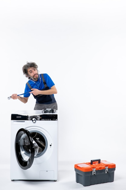 Vue de face du réparateur tenant un stéthoscope avec les deux mains debout derrière la rondelle sur un mur blanc