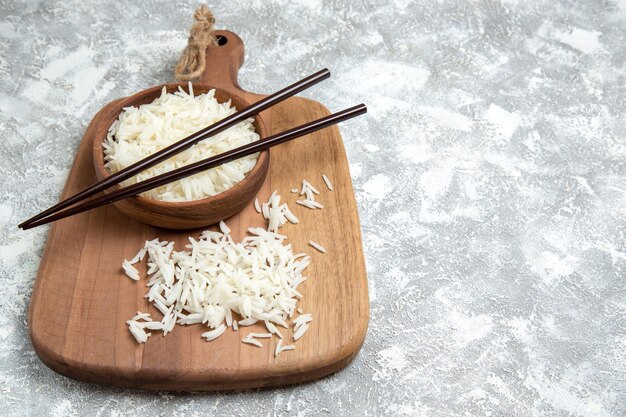 Vue De Face Du Riz Cuit Savoureux à L'intérieur D'une Assiette Brune Avec Des Bâtons Sur Un Espace Blanc