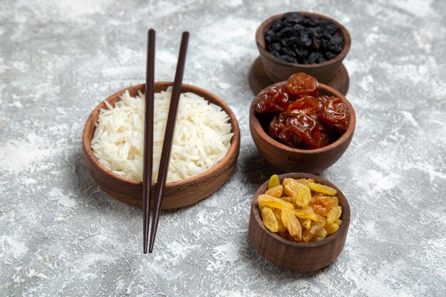 Vue de face du riz cuit savoureux à l'intérieur d'une assiette brune avec des raisins secs sur un espace blanc