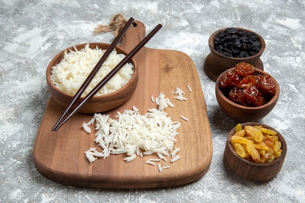 Vue de face du riz cuit savoureux à l'intérieur d'une assiette brune avec des raisins secs sur un espace blanc