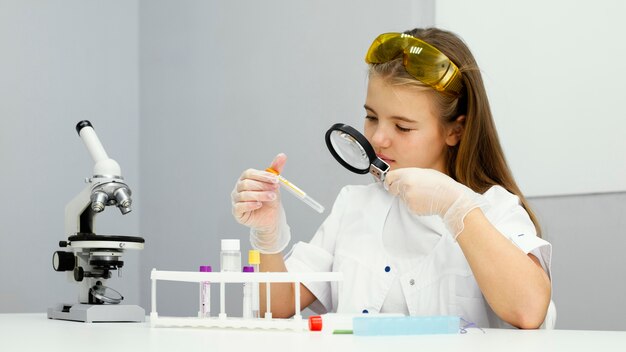 Vue de face du scientifique fille avec tube à essai et loupe