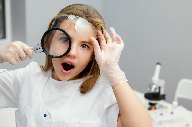 Vue de face du scientifique de la jeune fille à l'aide de la loupe