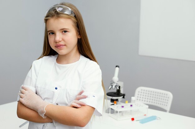 Vue de face du scientifique de la jeune fille posant en blouse de laboratoire