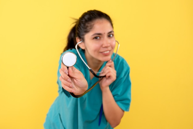 Vue de face du stéthoscope dans les mains des femmes sur le mur isolé jaune