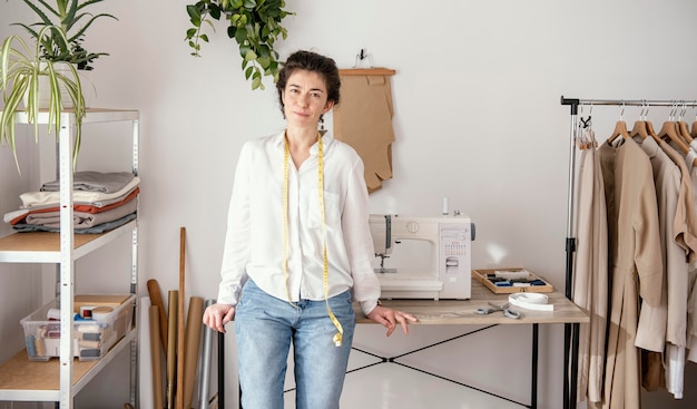 Vue de face du tailleur féminin posant dans le studio avec machine à coudre