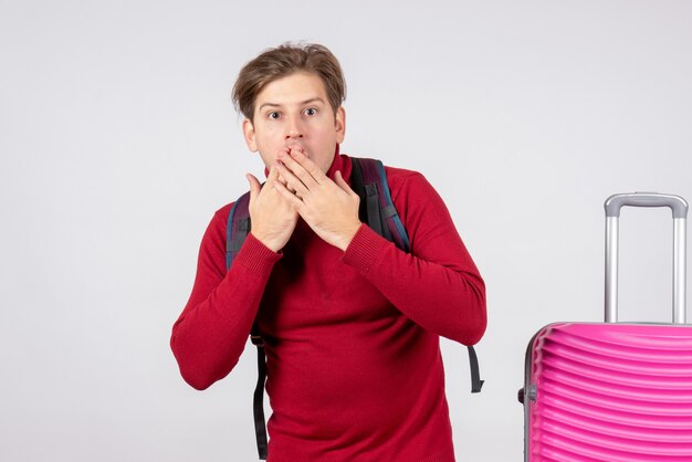 Vue de face du touriste masculin avec sac à dos sur mur blanc