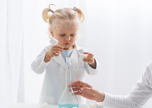 Vue de face du tout-petit mignon apprendre la science avec des guimauves