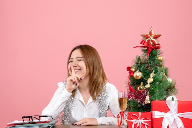 Vue de face du travailleur féminin assis derrière sa table avec des cadeaux sur rose