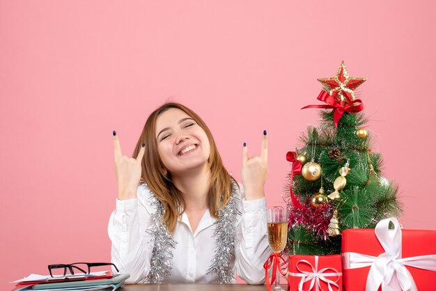 Vue de face du travailleur féminin assis derrière sa table avec des cadeaux sur rose