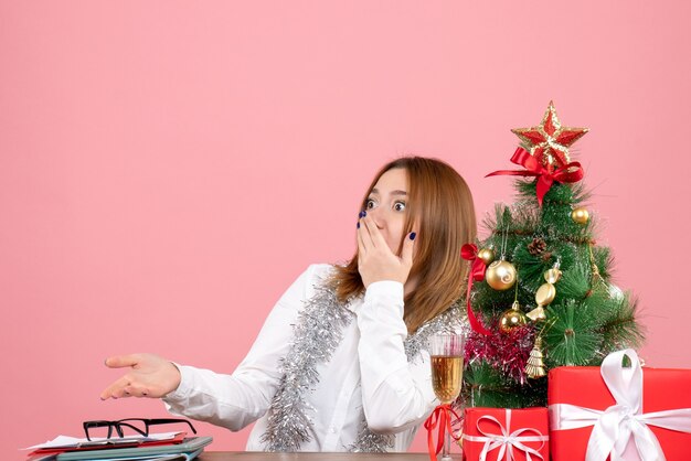 Vue de face du travailleur féminin autour de cadeaux de Noël avec visage choqué sur rose