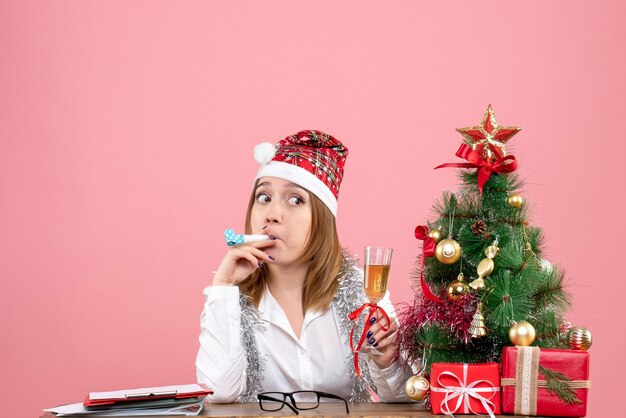 Vue de face du travailleur féminin tenant un verre de champagne sur rose