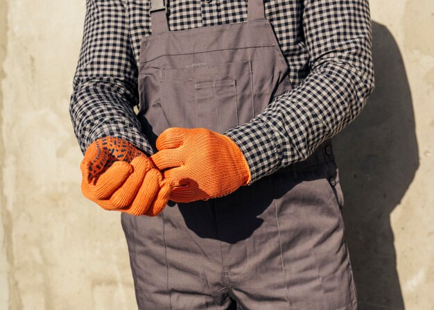 Vue de face du travailleur masculin en uniforme avec des gants de protection