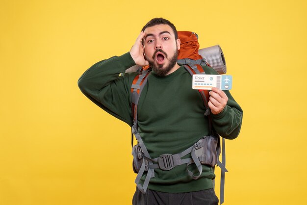 Vue de face du type de voyageur confus avec sac à dos debout sur fond jaune