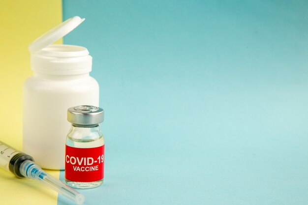 Vue de face du vaccin contre le coronavirus avec injection sur fond jaune-bleu virus de l'hôpital covid- science santé laboratoire de médicaments pandémie espace libre de couleur