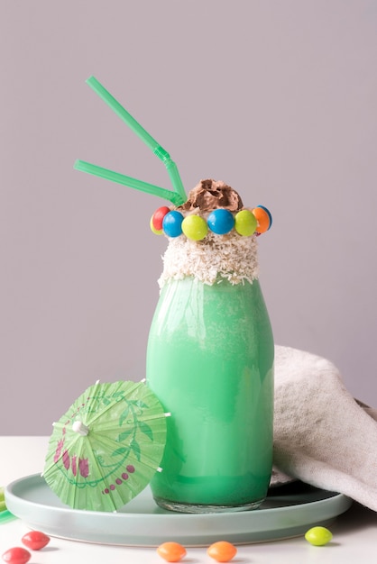 Photo gratuite vue de face du verre de dessert avec garniture de bonbons colorés et parapluie