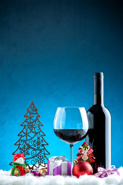 Vue de face du verre à vin et des détails de Noël de la bouteille sur fond bleu