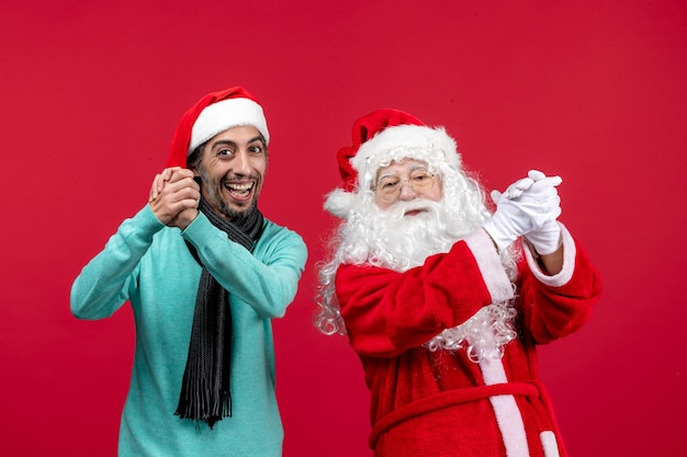 Vue de face du vieux père noël avec homme debout sur le mur rouge