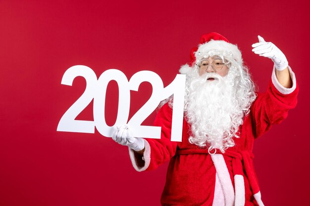 Vue de face du vieux père noël tenant l'écriture sur le mur rouge