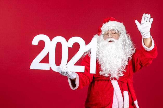 Vue de face du vieux père noël tenant l'écriture sur le mur rouge