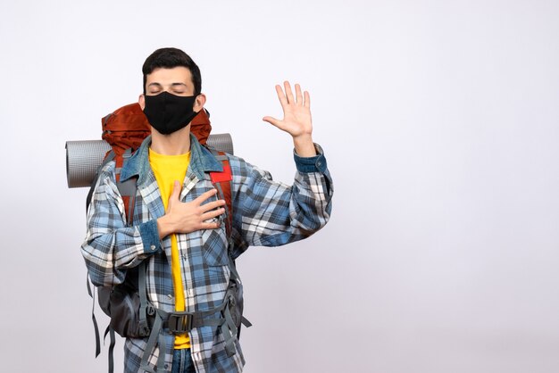 Vue de face du voyageur masculin avec sac à dos et masque prometteur avec geste de la main