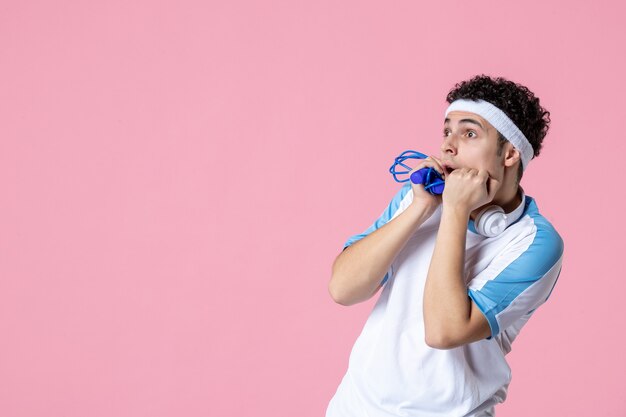 Vue de face effrayé jeune homme en vêtements de sport avec corde à sauter