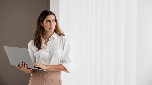 Vue de face de l'élégante femme d'affaires tenant un ordinateur portable avec espace de copie