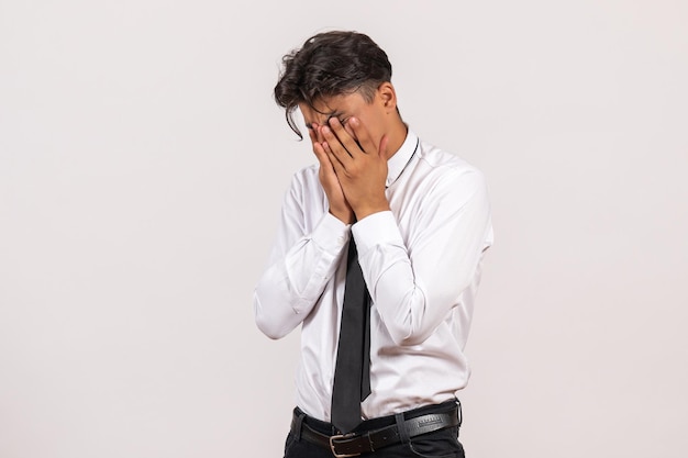 Vue de face employé de bureau masculin couvrant son visage sur un mur blanc travail de bureau homme humain