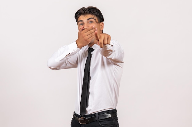 Photo gratuite vue de face employé de bureau masculin pointant avec un visage choqué sur un mur blanc travail masculin