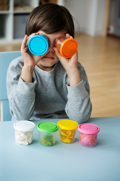 Vue de face enfant jouant avec de la pâte à modeler à l'intérieur