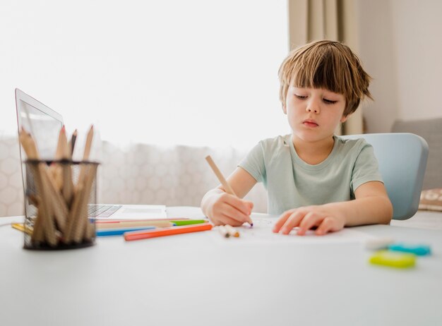 Vue de face de l'enfant qui écrit et apprend à la maison