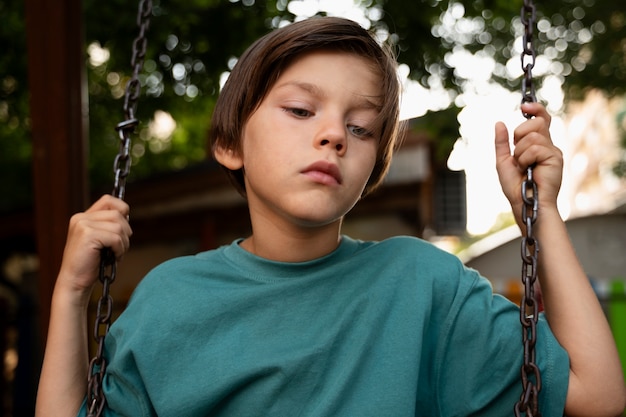 Photo gratuite vue de face enfant triste sur balançoire