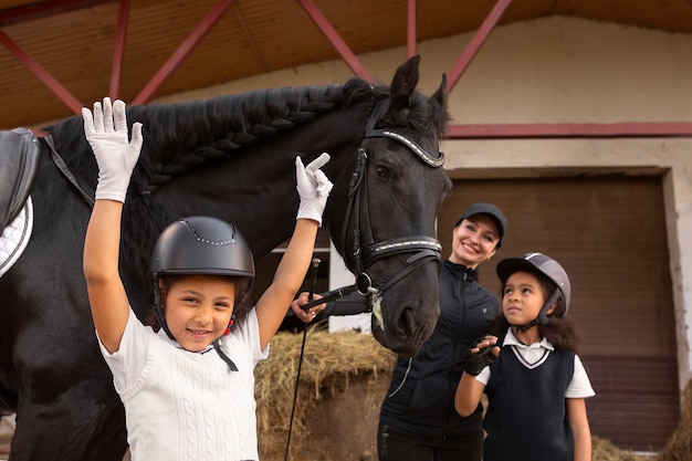 Photo gratuite vue de face des enfants apprenant à monter à cheval