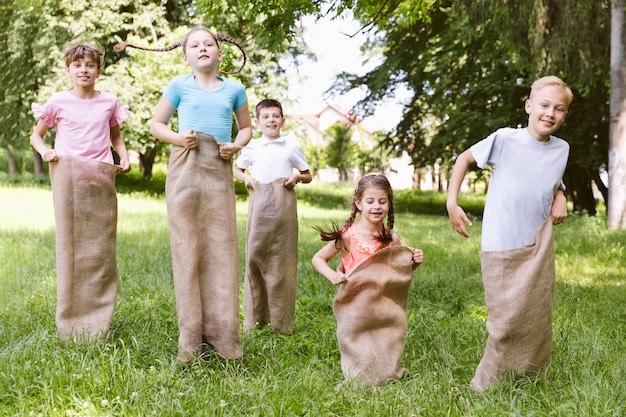 Photo gratuite vue de face des enfants en compétition avec des sacs de jute