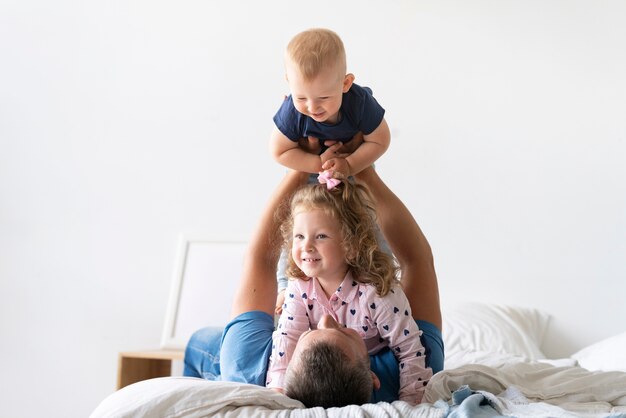 Vue de face des enfants heureux jouant avec le père