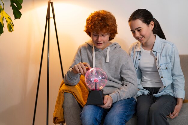 Photo gratuite vue de face des enfants interagissant avec une boule de plasma